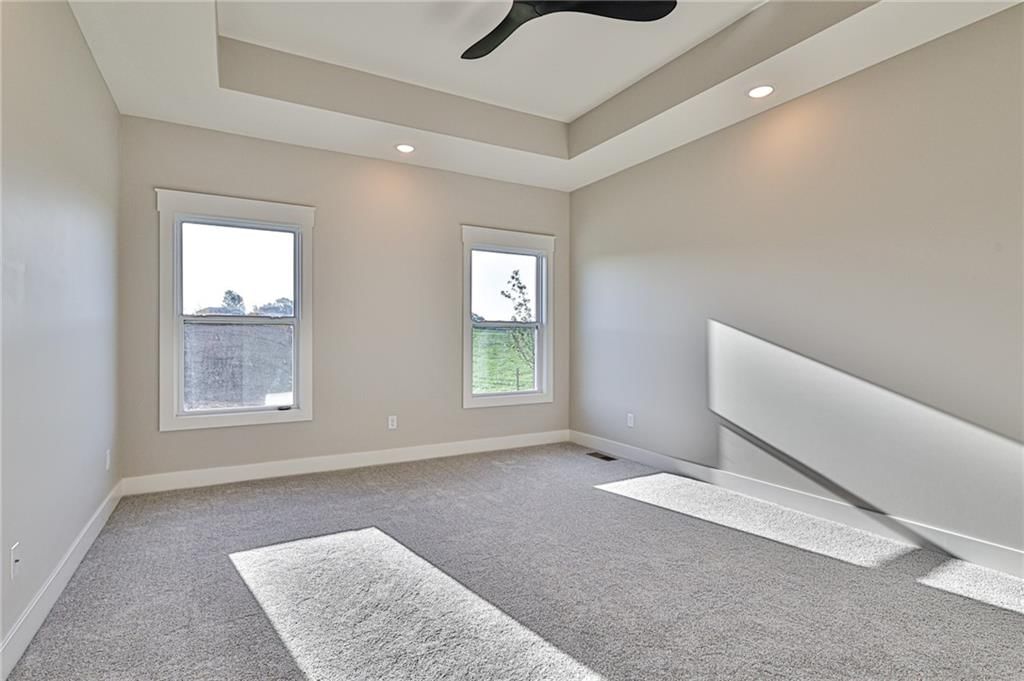 Main-floor primary bedroom, tray ceiling and carpet at 14014 Crawford Creek Circle, Lake Lotawana, MO 64034