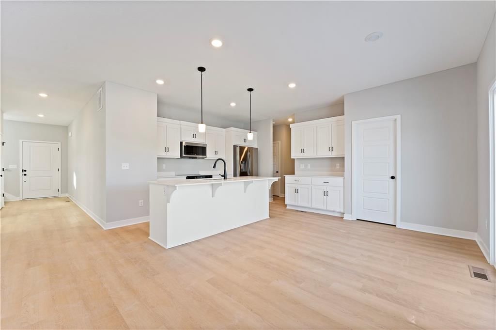 Open floor plan, kitchen island and white kitchen at 1503 SW Meadowlark Court, Oak Grove, MO 64075