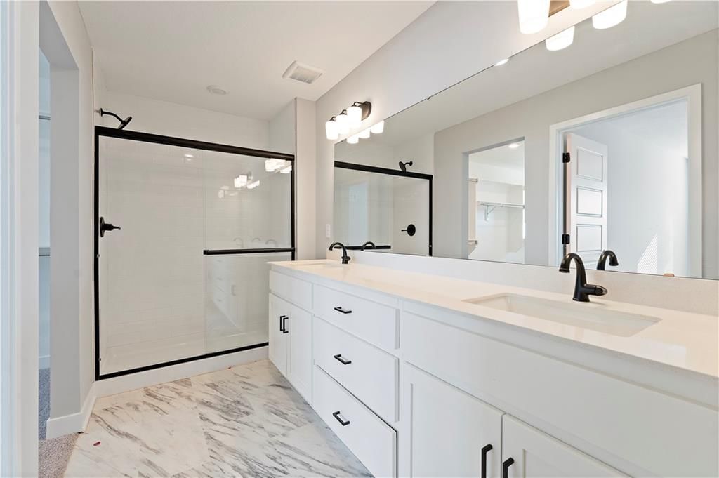 Tiled shower, double vanity and frameless glass shower at 1503 SW Meadowlark Court, Oak Grove, MO 64075