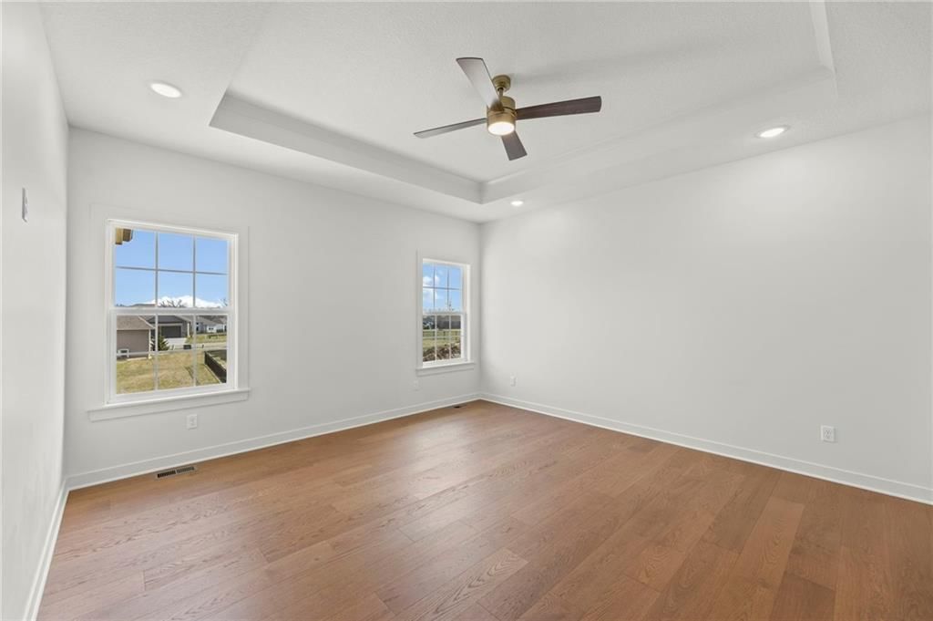 Main-floor primary bedroom and tray ceiling at 4467 Tee Box Drive, Basehor, KS 66007