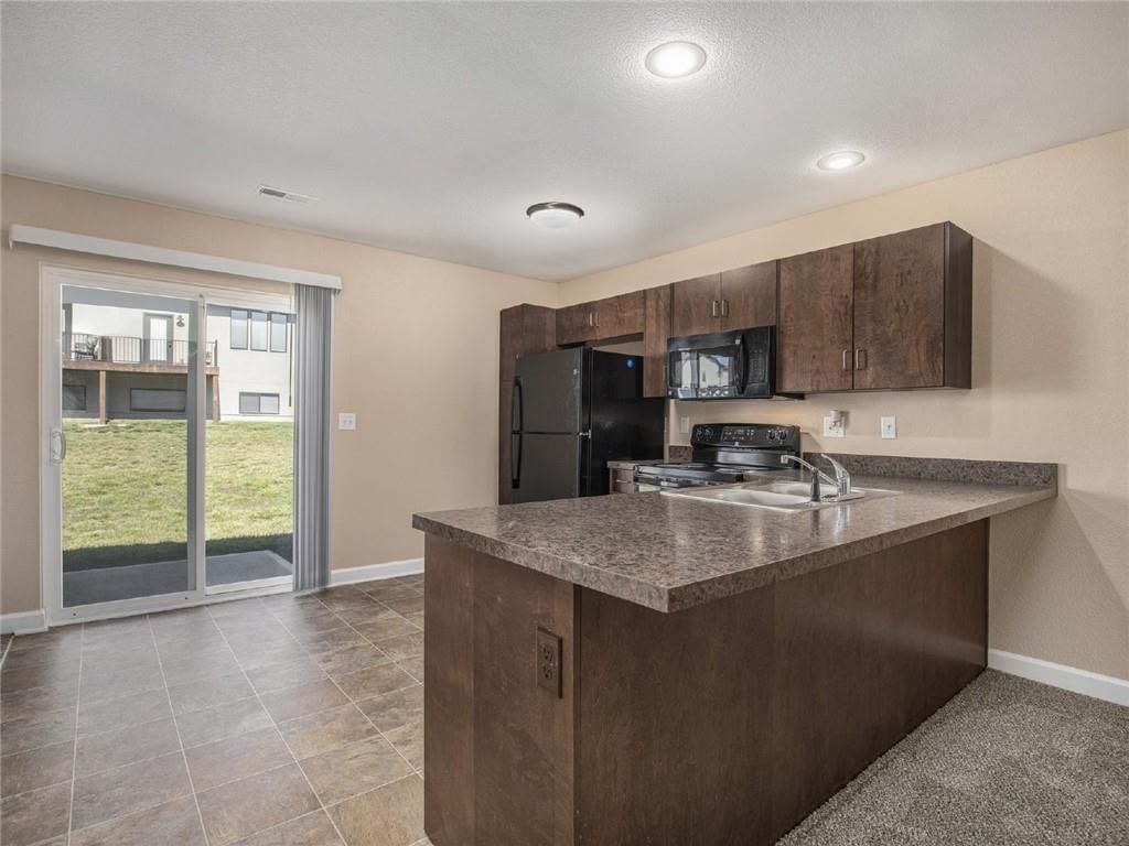 Open floor plan, kitchen island and granite counters at 254 Pointe Lane, Raymore, MO 64083
