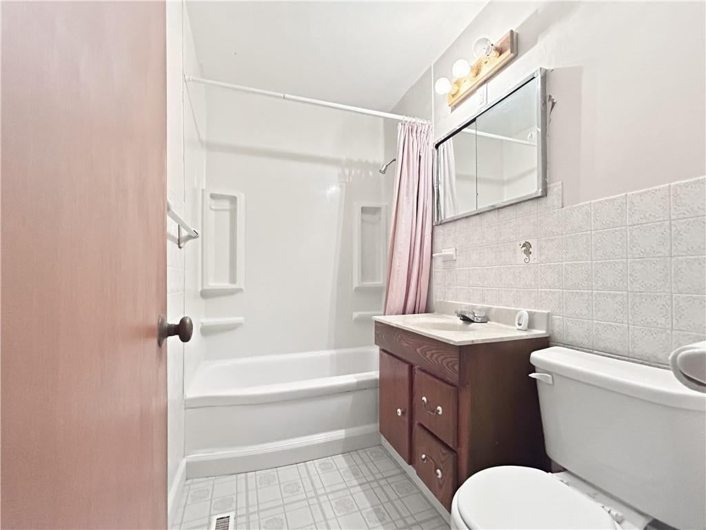 Tiled shower and wood vanity at 505 NE 67th Terrace, Gladstone, MO 64118