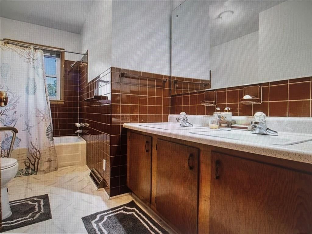Tiled shower and wood vanity at 9723 E 13th Street S, Independence, MO 64052