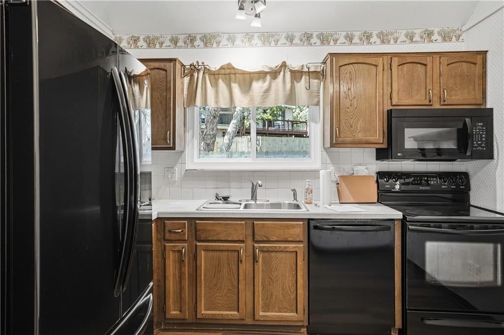 Wood kitchen cabinets, electric range and black appliances at 5970 N Bellefontaine Avenue, Gladstone, MO 64119