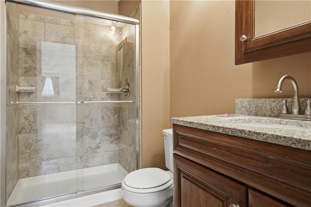 Tiled shower, frameless glass shower and wood vanity at 5970 N Bellefontaine Avenue, Gladstone, MO 64119
