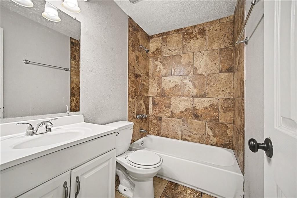 Tiled shower, white vanity and black hardware at 9038 Manning Avenue, Kansas City, MO 64138