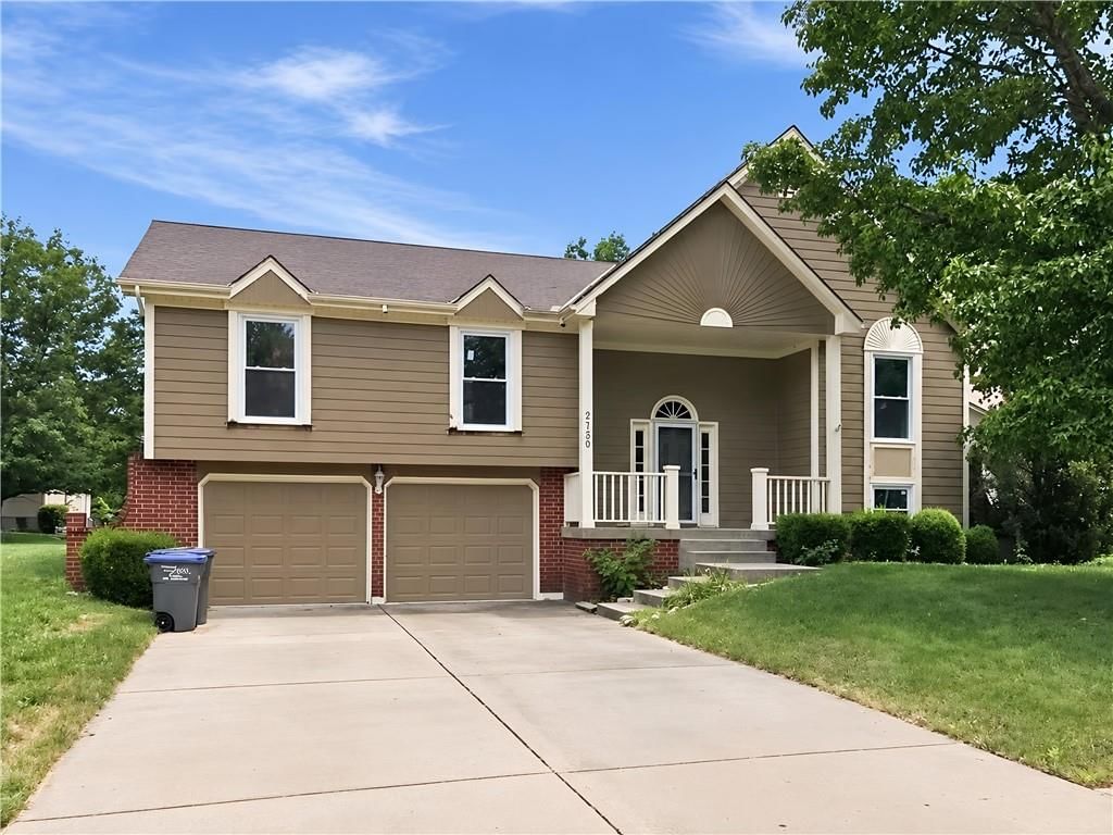 Covered front porch, attached garage and gray roof at 2129 Sunset Circle, Pleasant Hill, MO 64080