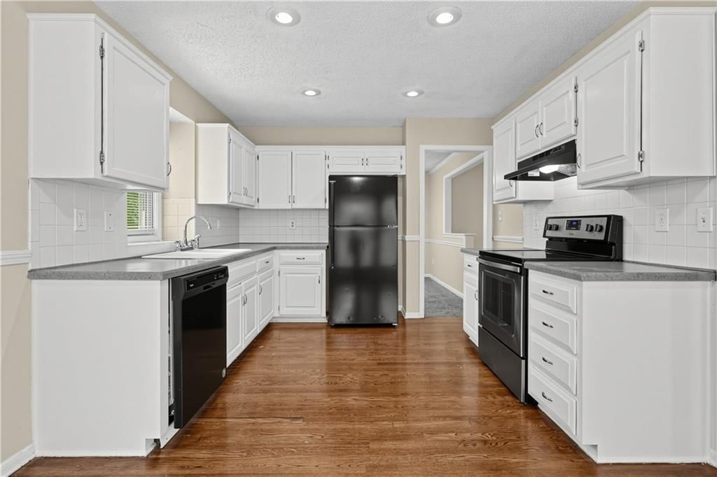 Open floor plan, hardwood floors and white kitchen at 2129 Sunset Circle, Pleasant Hill, MO 64080