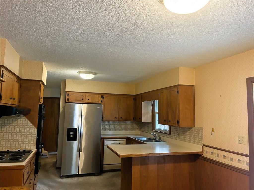 Stainless steel appliances, wood kitchen cabinets and kitchen backsplash at 1212 SW Horizon Drive, Blue Springs, MO 64015