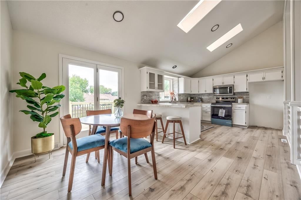 Kitchen island, hardwood floors and white kitchen at 1105 Brookside Place, Raymore, MO 64083