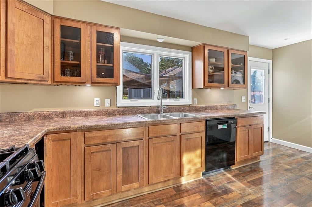Wood kitchen cabinets, black appliances and beige or brown countertops at 3007 W 73rd Terrace, Prairie Village, KS 66208