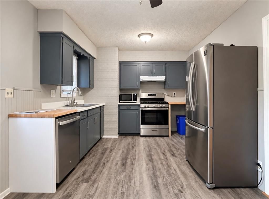 Butcher block countertops, gray kitchen cabinets and stainless steel appliances at 11806 E 58th Street, Kansas City, MO 64133