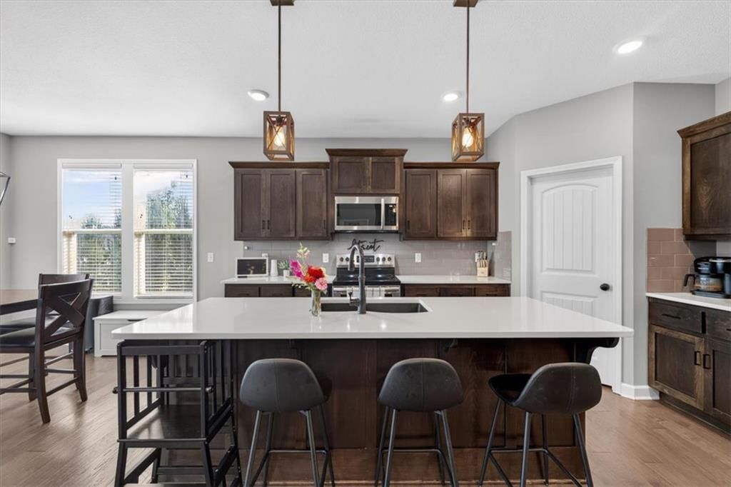 Kitchen island, hardwood floors and quartz counters at 504 Bentwater Drive, Raymore, MO 64083