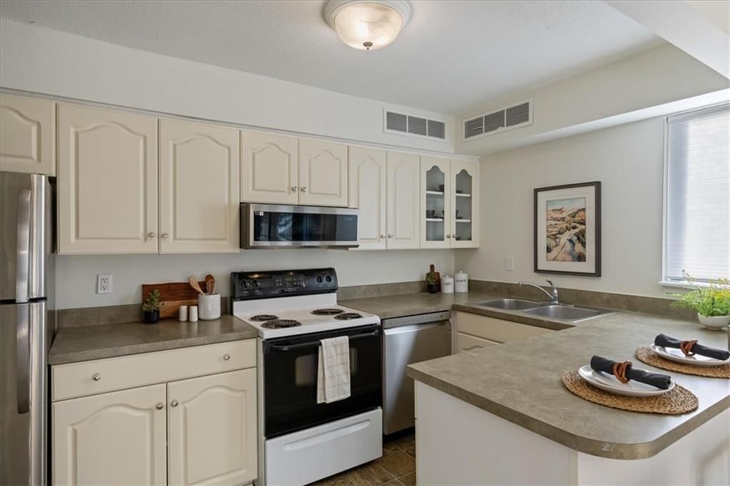 Off-white kitchen cabinets, stainless steel appliances and electric range at 4057 Walnut Street #6, Kansas City, MO 64111