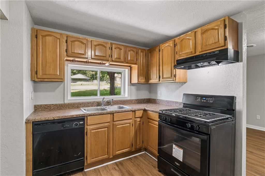 Gas range, wood kitchen cabinets and black appliances at 5304 Maywood Avenue, Raytown, MO 64133