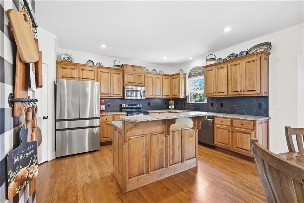 Kitchen island, granite counters and stainless steel appliances at 110 S Eastglen Drive, Raymore, MO 64083