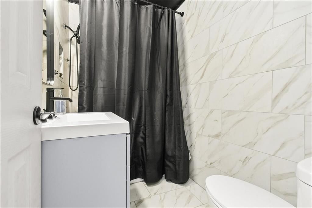 Tiled shower, wood vanity and renovated bathrooms at 1708 N Kiger Road, Independence, MO 64050
