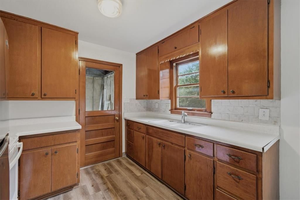 Wood kitchen cabinets, kitchen backsplash and white countertops at 909 E 100th Terrace, Kansas City, MO 64131