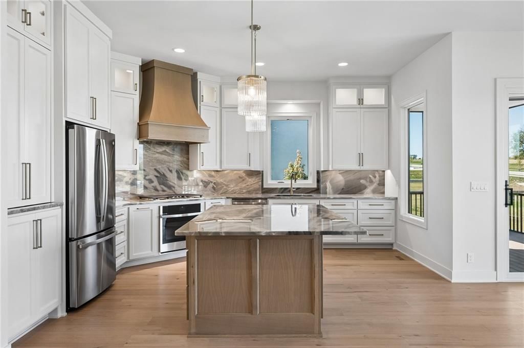 Kitchen island, white kitchen and gas range at 13725 Pembroke Lane, Leawood, KS 66224