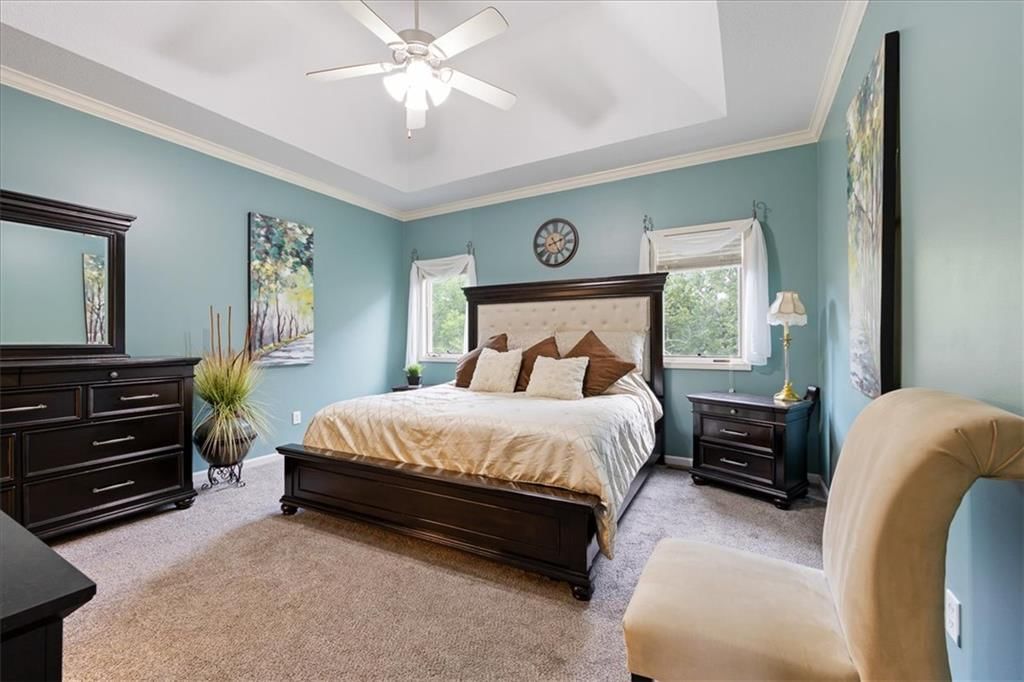 Main-floor primary bedroom, statement lighting and tray ceiling at 1829 SW Twincreek Place, Blue Springs, MO 64015