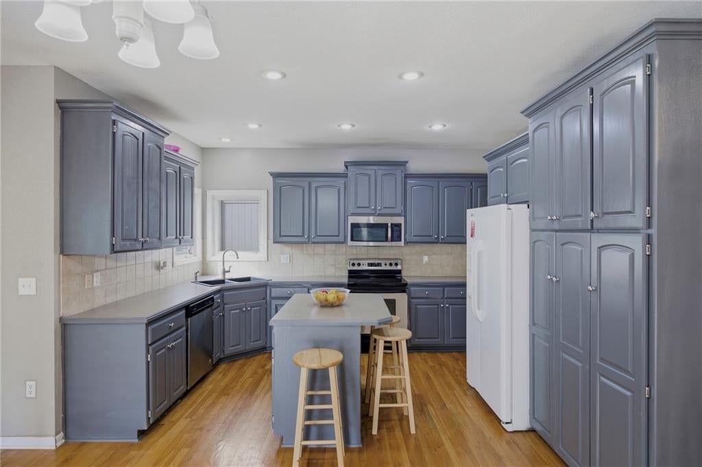 Kitchen island, gray kitchen cabinets and electric range at 361 W Westhoff Place, Gardner, KS 66030