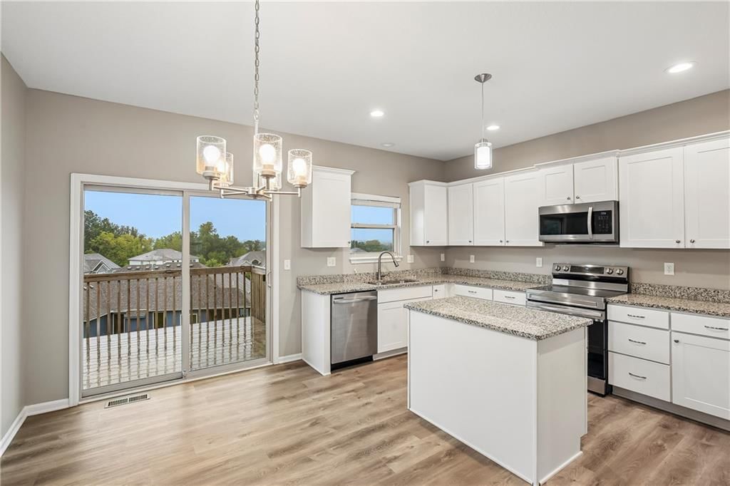 Kitchen island, white kitchen and granite counters at 1208 NW Hilltop Lane, Grain Valley, MO 64029