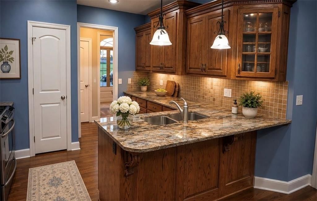 Kitchen island, hardwood floors and statement lighting at 907 Order No. 11, Freeman, MO 64746