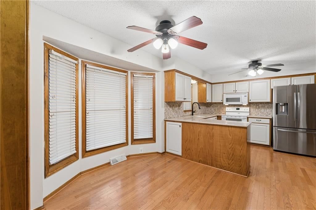 Kitchen island, hardwood floors and two-tone kitchen cabinets at 617 W Maple Street, Raymore, MO 64083