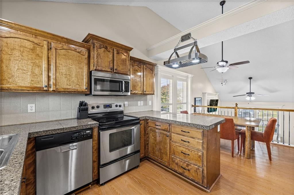 Granite counters, stainless steel appliances and wood kitchen cabinets at 1113 Creekside Court, Raymore, MO 64083