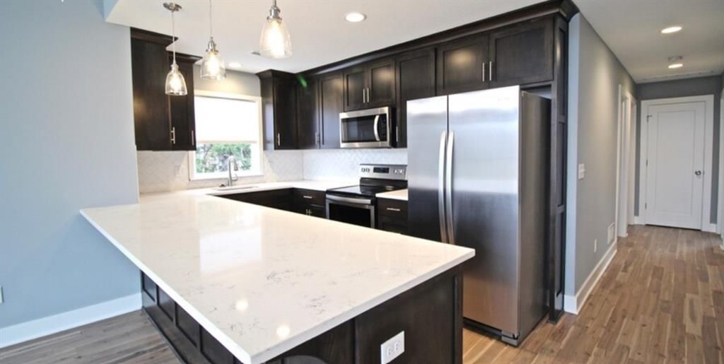 Kitchen island, statement lighting and stainless steel appliances at 3915 Kenwood Avenue, Kansas City, MO 64110