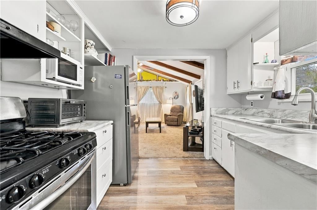 Open floor plan, gas range and mixed-finish appliances at 1009 E 134th Street, Grandview, MO 64030