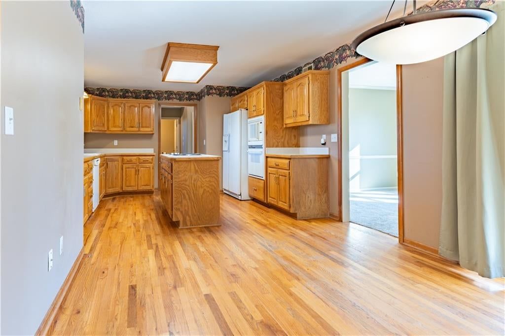Kitchen island, hardwood floors and double oven at 3725 SW Evergreen Lane, Lee's Summit, MO 64082