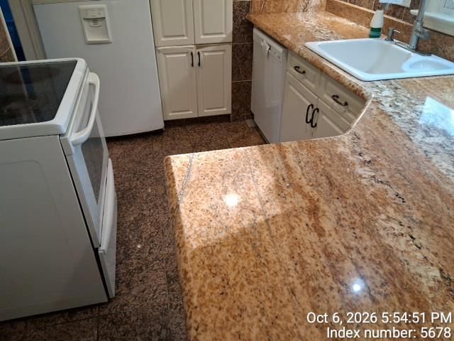 Off-white kitchen cabinets, granite counters and white appliances at 7020 Raytown Road, Raytown, MO 64133