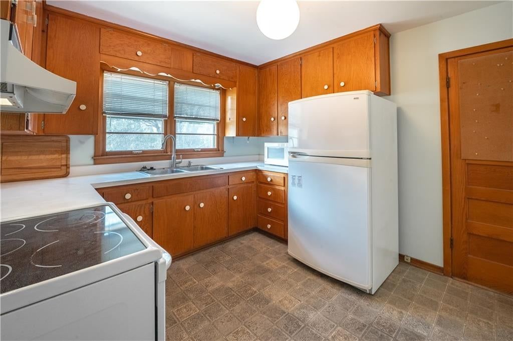 Wood kitchen cabinets, white appliances and electric range at 5820 N Lenox Avenue, Kansas City, MO 64151