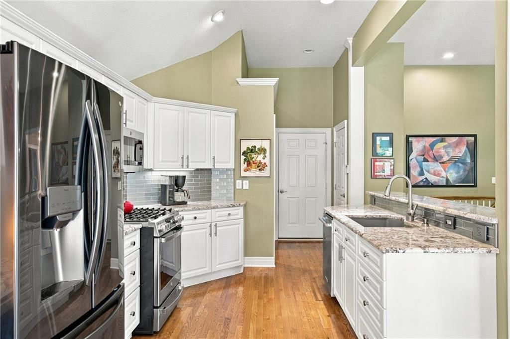 White kitchen, granite counters and gas range at 624 W 131 Terrace, Kansas City, MO 64145