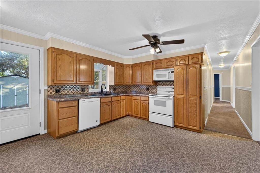 Open floor plan, wood kitchen cabinets and white appliances at 340 Champ Street, Peculiar, MO 64078