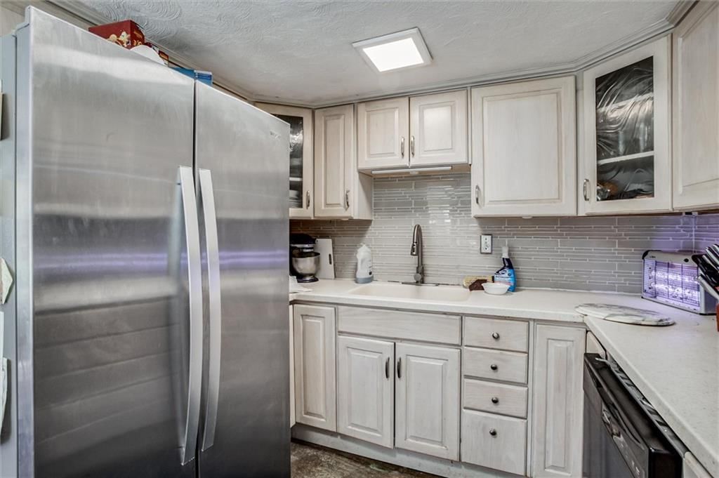 Off-white kitchen cabinets, stainless steel appliances and kitchen backsplash at 31103 E 315TH Street, Garden City, MO 64747