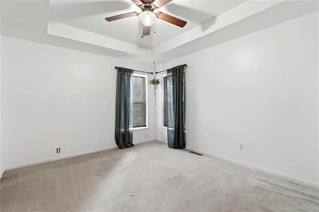 Main-floor primary bedroom, tray ceiling and carpet at 1302 Deena Street, Pleasant Hill, MO 64080