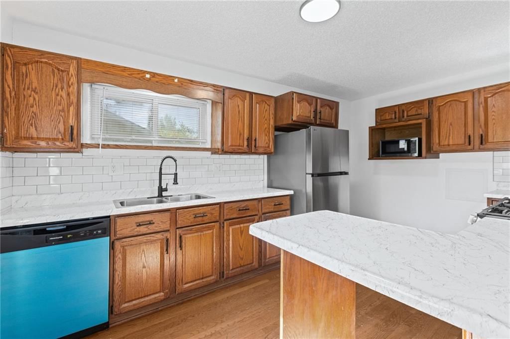 Stainless steel appliances, wood kitchen cabinets and kitchen backsplash at 6912 N Harrison Street, Gladstone, MO 64118