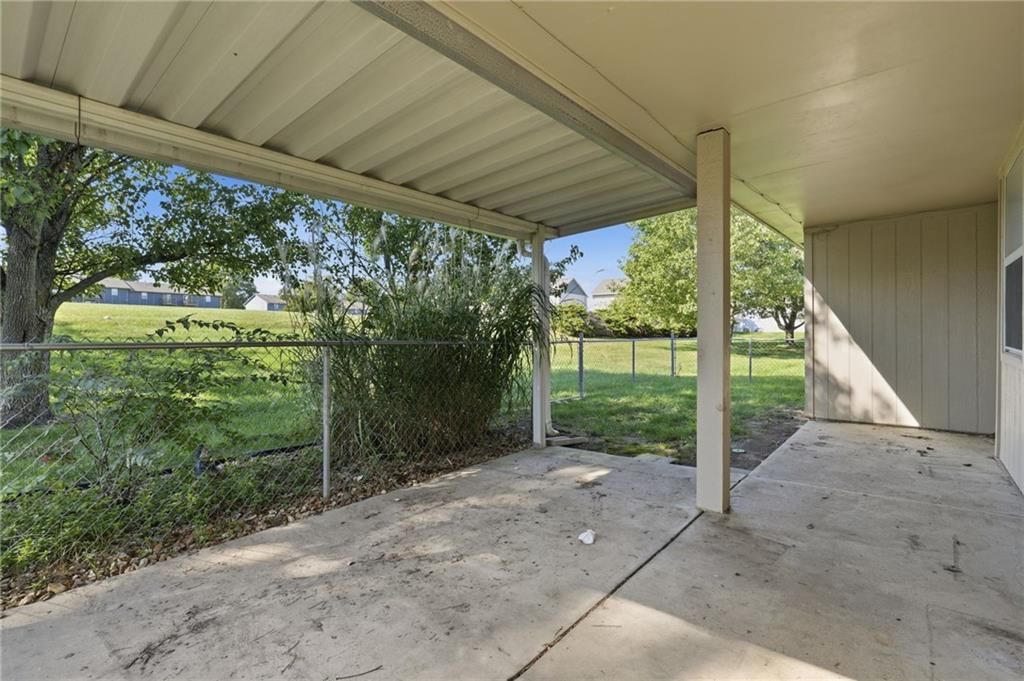 Mature trees, covered patio and concrete patio at 502 S Saturn Drive, Raymore, MO 64083