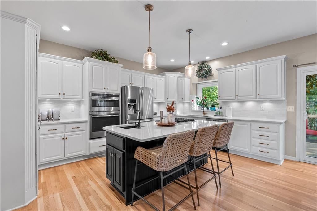 Kitchen island, white kitchen and gas range at 15815 E 76th Street, Kansas City, MO 64139