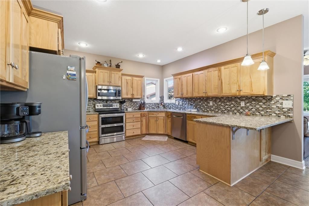 Kitchen island, statement lighting and granite counters at 27423 New Lancaster Road, Louisburg, KS 66053