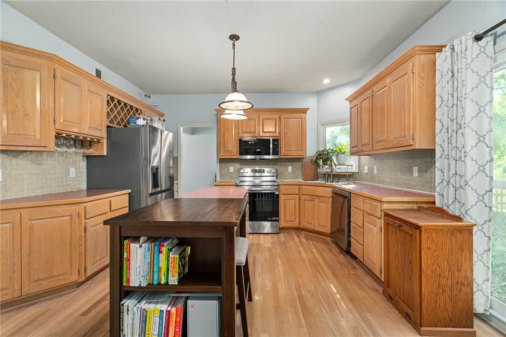 Kitchen island, stainless steel appliances and kitchen backsplash at 11229 W 117th Street, Overland Park, KS 66210