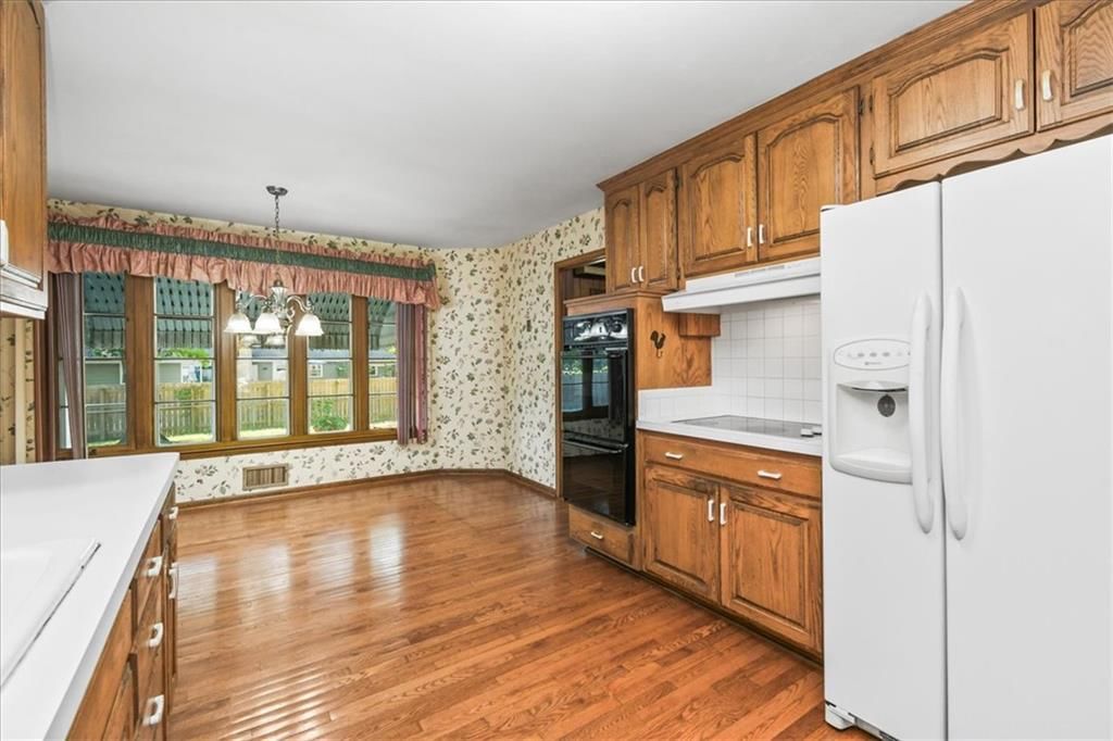 Breakfast nook, wood kitchen cabinets and white appliances at 11000 Washington Street, Kansas City, MO 64114