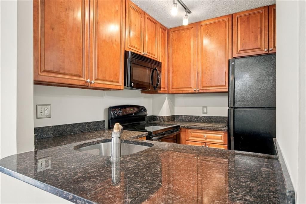 Granite counters, wood kitchen cabinets and electric range at 3838 Rainbow Boulevard #101, Kansas City, KS 66103