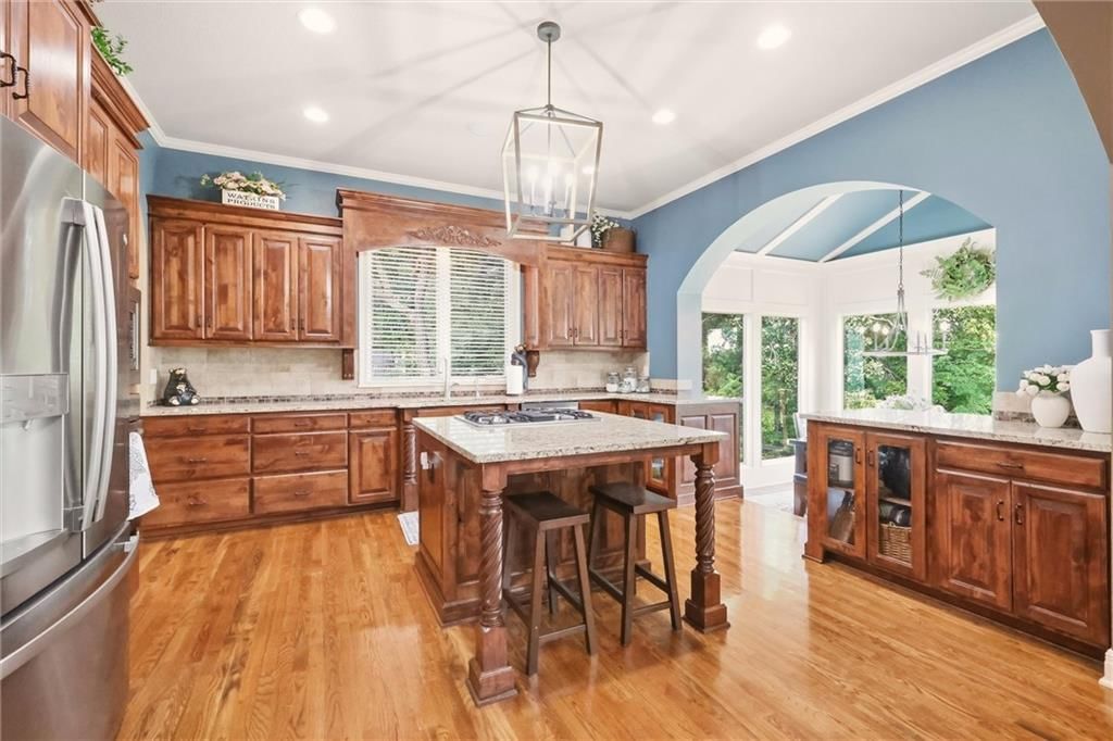 Kitchen island, hardwood floors and statement lighting at 20108 W 92nd Street, Lenexa, KS 66220