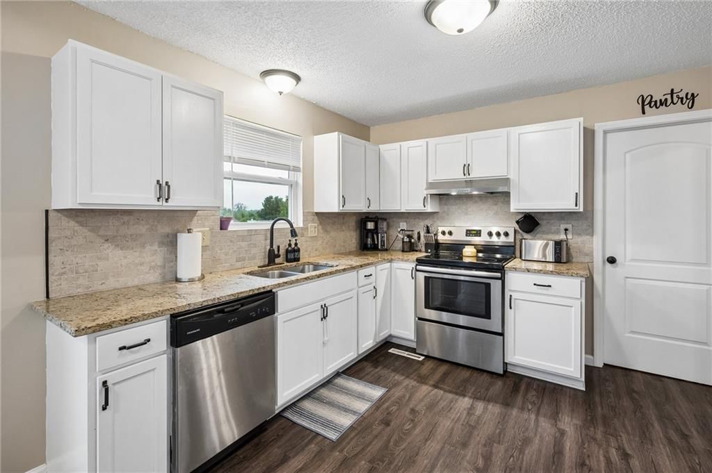 White kitchen, granite counters and stainless steel appliances at 1432 NW Yankee Drive, Blue Springs, MO 64015