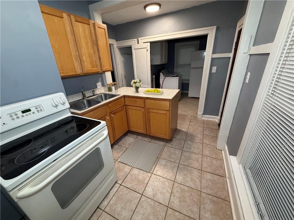 Tile floors, wood kitchen cabinets and white appliances at 4412 Cambridge Street, Kansas City, KS 66103
