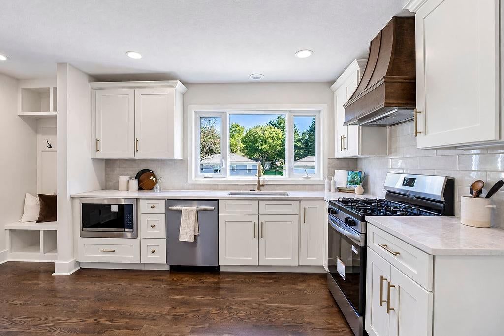 White kitchen, quartz counters and gas range at 9931 Woodson Drive, Overland Park, KS 66207