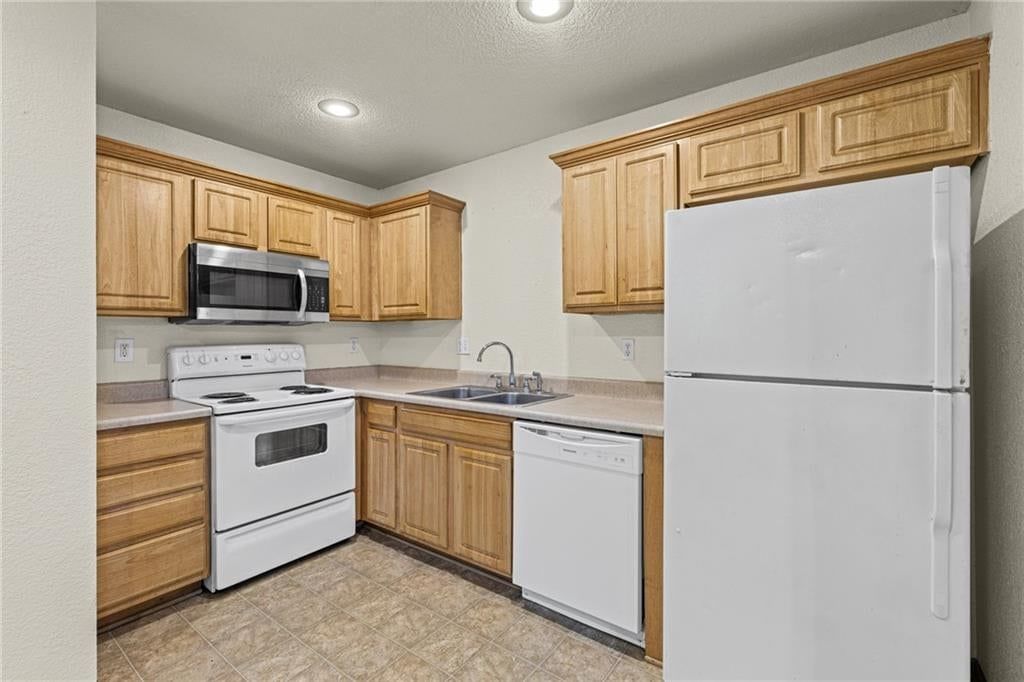 Wood kitchen cabinets, white appliances and electric range at 18501 E 3rd Street Court N, Independence, MO 64056